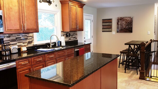 Una cocina con armarios de madera, encimera de granito y ventana.