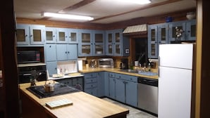 Cucina con mobili blu, un piano di lavoro in legno, un forno a microonde, un tostapane e un frigorifero.