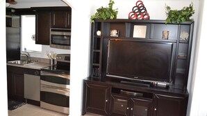 A modern kitchen with dark cabinetry, stainless steel appliances, and a built-in flat-screen TV. - Oceanfront!!! Clean and Cozy, Free Wi-Fi & calls to US and Canada (Lauderdale-by-the-Sea)