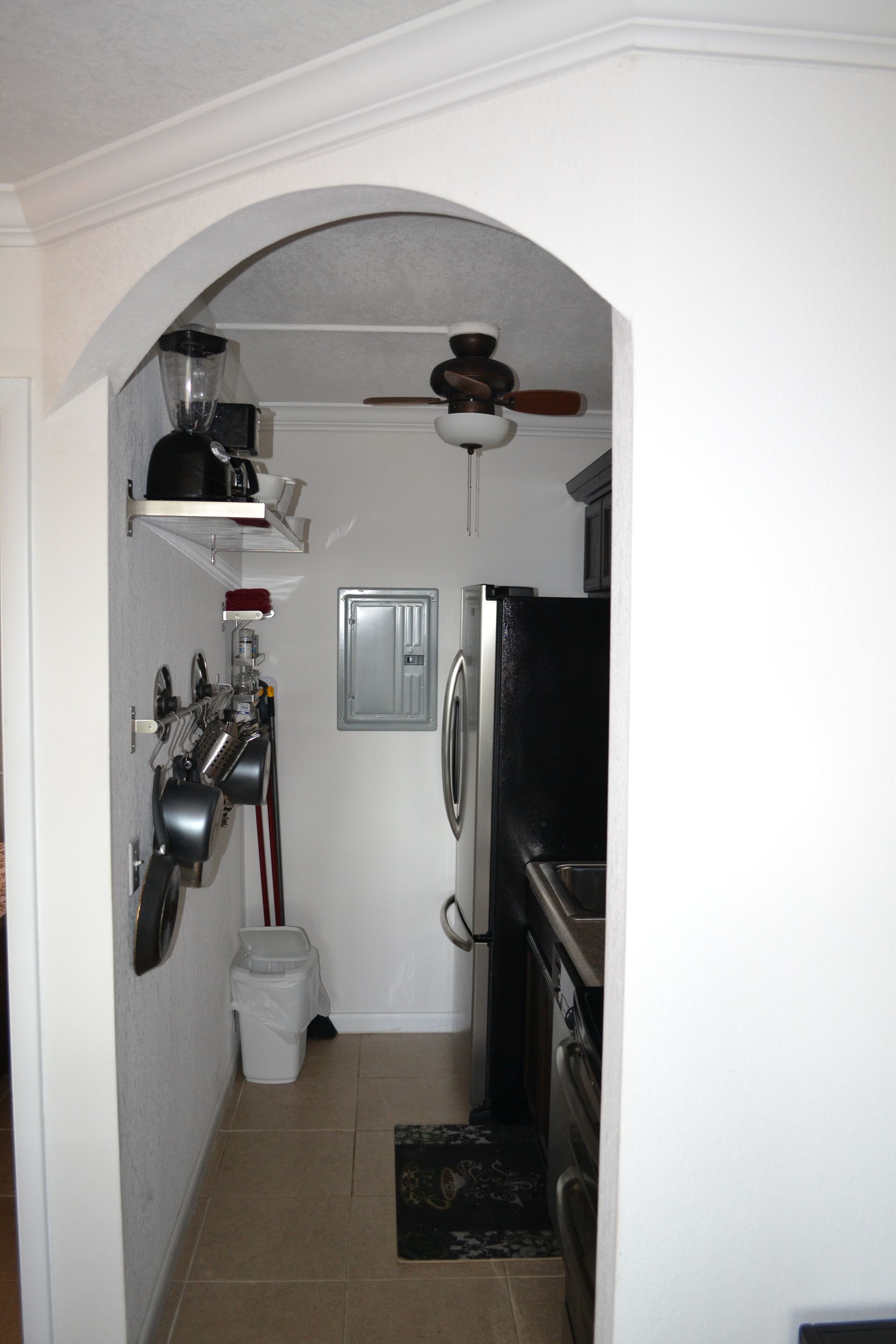 Cocina compacta con refrigerador, horno y ventilador de techo.