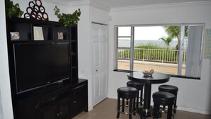 A modern kitchen with a flat-screen TV, black bar stools, and a window with a view of the beach. - Oceanfront!!! Clean and Cozy, Free Wi-Fi & calls to US and Canada (Lauderdale-by-the-Sea)