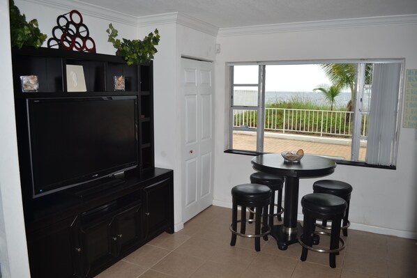 A modern kitchen with a flat-screen TV, black bar stools, and a window with a view of the beach. - Oceanfront!!! Clean and Cozy, Free Wi-Fi & calls to US and Canada (Lauderdale-by-the-Sea)