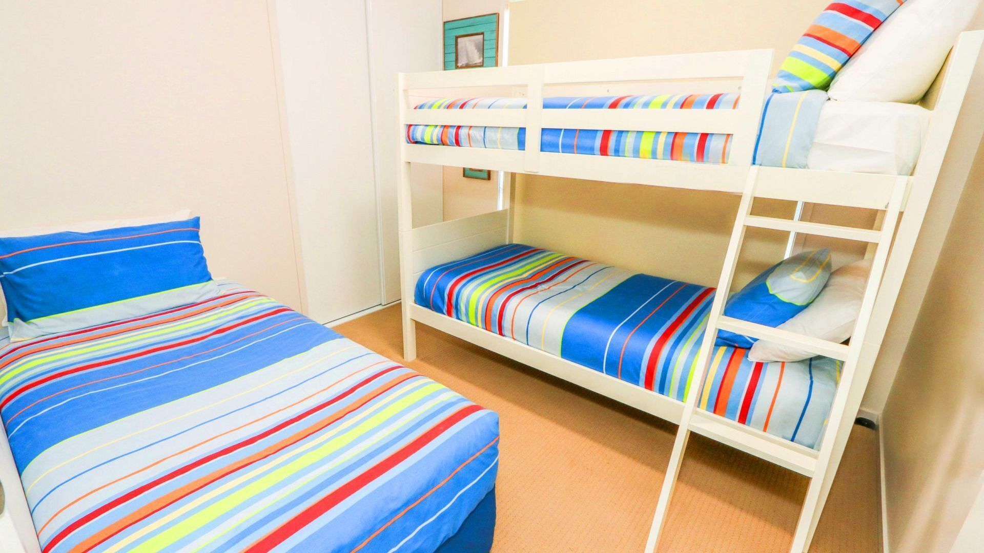 Ein Stockbett mit farbenfroher, gestreifter Bettwäsche und Kissen.