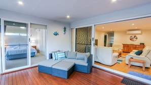A modern interior with a large sliding glass door leading to a balcony, a cozy seating area with a sofa and cushions, and a living room with a sofa and chairs.