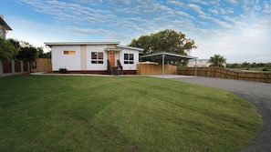 A single-story house with a covered patio, a front yard, and a wooden fence.