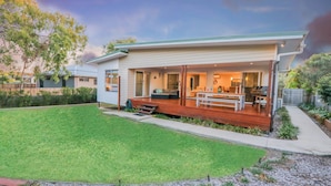 A modern house with a covered patio, a well-maintained lawn, and a barbecue area.