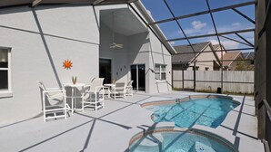 Une piscine extérieure couverte, décorée d’un motif en forme de soleil, avec des chaises blanches et un ventilateur de plafond.