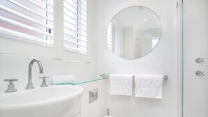 Een moderne badkamer met een wit wastafelmeubel, toilet en een douchecabine met glazen wanden.