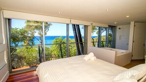 A bedroom with a large window offering a view of the sea and trees. - TREE HOUSE - SUNRISE AT 1770 (AGNES WATER)