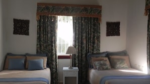 Une chambre avec deux lits, une table de chevet et des rideaux.