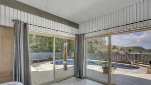 Quarto com uma grande porta de correr de vidro que dá para uma área de piscina externa.