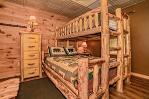 Una habitación rústica tipo cabaña con literas, un aparador y una lámpara.