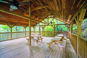 Una terraza de madera con mesas de picnic y un ventilador de techo.