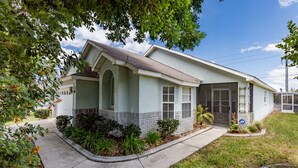 A single-story house with a front porch, a garage, and a small front yard with landscaping. - Beautiful villa in popular Indian Creek (Kissimmee)