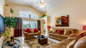 A spacious living room with two leather sofas, a glass coffee table, and a flat-screen TV. - Beautiful villa in popular Indian Creek (Kissimmee)