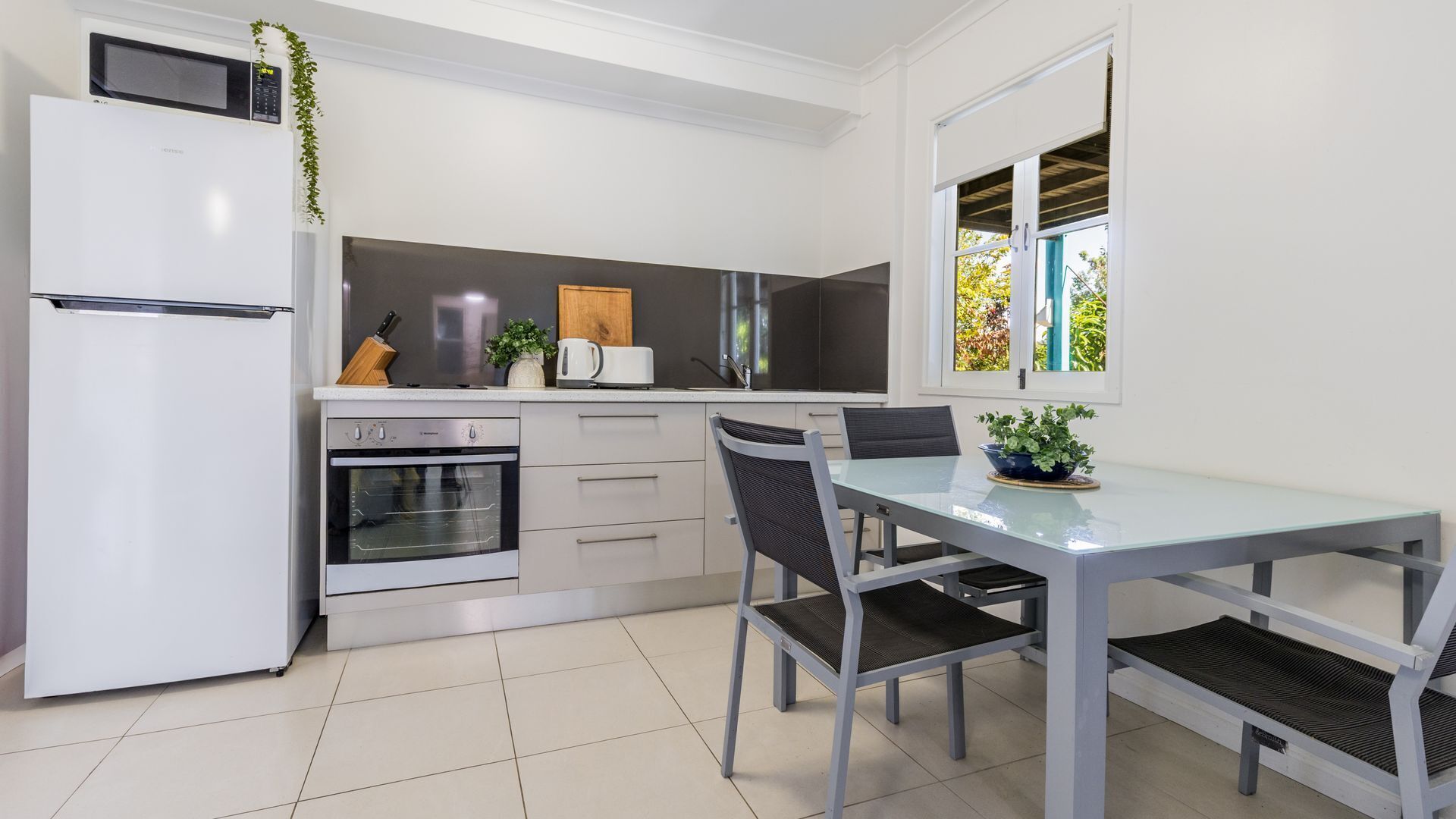 Une cuisine moderne équipée d’un réfrigérateur, d’un four, d’un four à micro-ondes et d’un coin repas avec une table et des chaises.