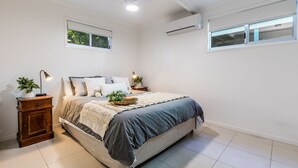 Un dormitorio con cama, mesitas de noche, ventana y equipo de aire acondicionado.