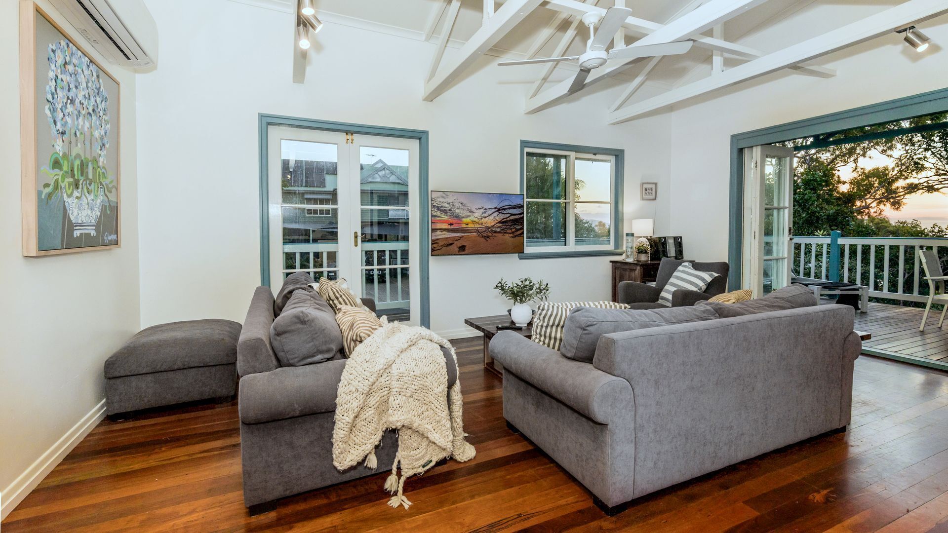 A spacious living room with grey sofas, a large window, and a view of the outdoors.
