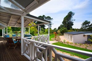 Relax on the covered deck, surrounded by lush greenery and a serene atmosphere.