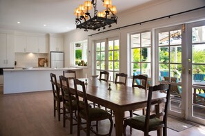 Enjoy meals at the central dining table surrounded by comfortable chairs, with views of the surrounding greenery.