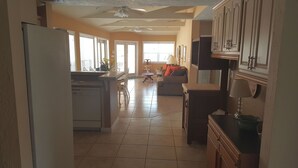 Una cocina amplia con zona de comedor, ventanas grandes y ventilador de techo.