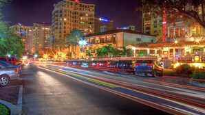 Vista nocturna de una calle con edificios, un motel y vehículos.