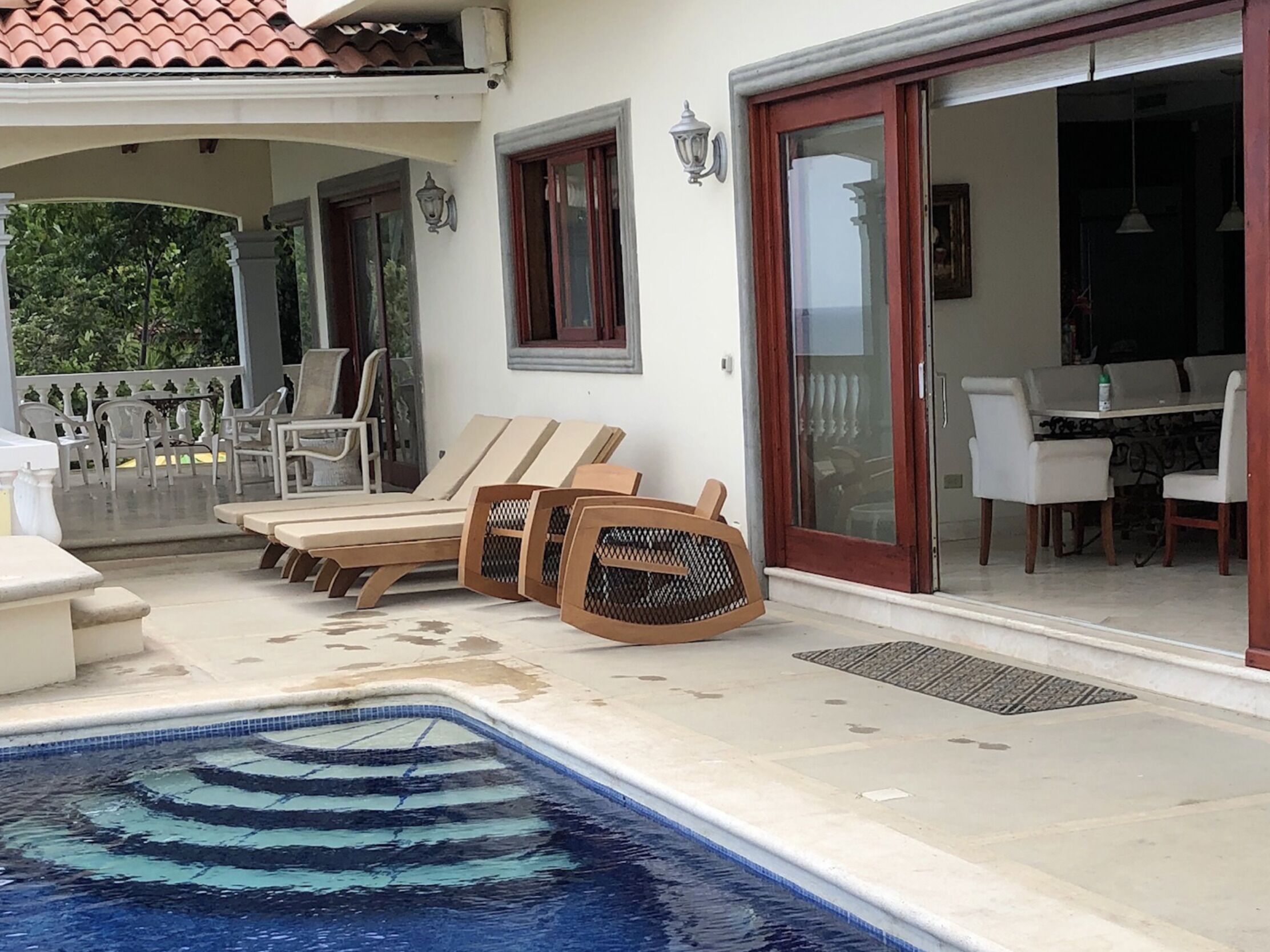 Uma área de piscina com espreguiçadeiras e uma mesa de jantar.