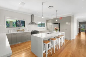 A modern kitchen with a large island, grey cabinetry, and a wooden floor. - Stunning Mystique Country House with lake & mountain. 15% discount all winter. (Coolangatta)