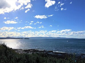 A coastal landscape with a clear sky, calm sea, and distant landforms.