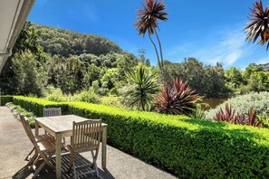 A wooden table and chairs set outdoors with a view of a lake and a forested hillside. - Stunning Mystique Country House with lake & mountain. 15% discount all winter. (Coolangatta)