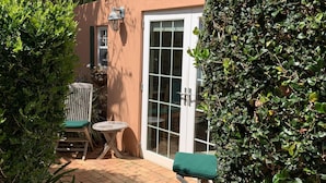Eine Terrasse mit Backsteinboden, einer weißen Tür und einer grünen Bank.