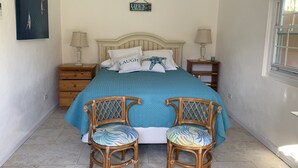 Ein Schlafzimmer mit einem Bett, zwei Stühlen, einem Nachttisch, einer Lampe und einem Schild an der Wand.