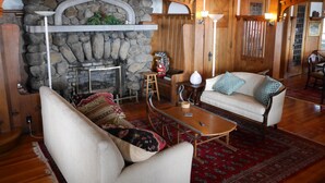 A cozy living room with a stone fireplace, wooden beams, a sofa, and a coffee table.