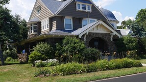 A two-story house with a stone foundation, a gabled roof, and a front porch.