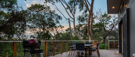 An outdoor deck with a barbecue grill, dining table, and chairs.