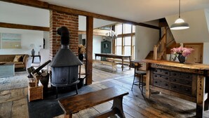 A rustic interior with exposed brick walls, a large fireplace, wooden furniture, and a staircase leading to an upper level. - Long View Farm on Broad Bay (Waldoboro)