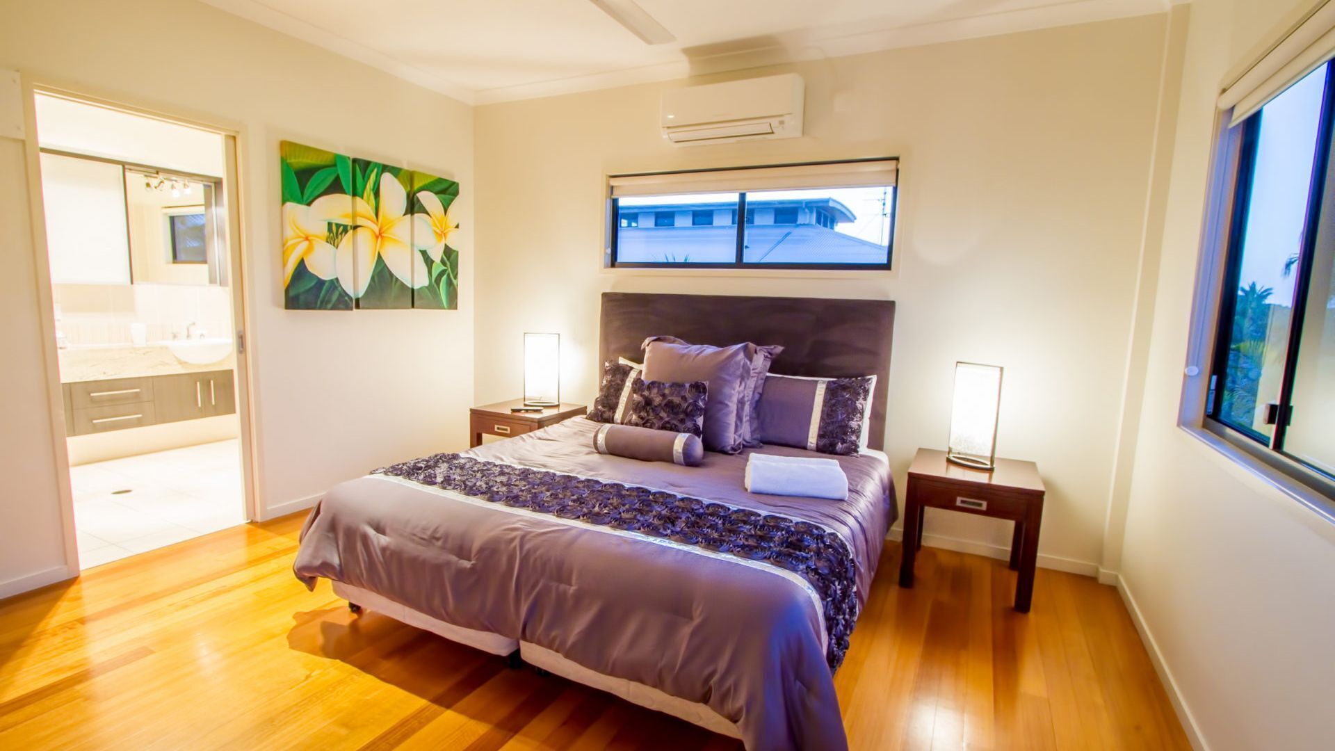 Een slaapkamer met een bed, nachtkastjes, een raam en een schilderij.