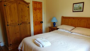 Un dormitorio con una cama grande, un armario de madera y una mesita de noche con lámpara.