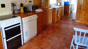 Una cocina con estufa, horno, lavavajillas y armarios de madera.
