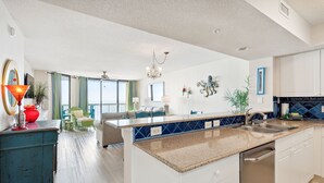 Una cocina amplia con una isla central, armarios blancos y salpicadero azul.