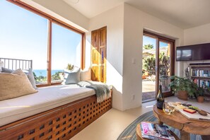 Enjoy a comfortable seating area with a sofa, television, and bookshelf, offering a view of the sea.