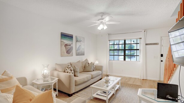 A living room with a sofa, coffee table, and a laptop on a small table. - Charming Cottage worth every $$ (Delray Beach)