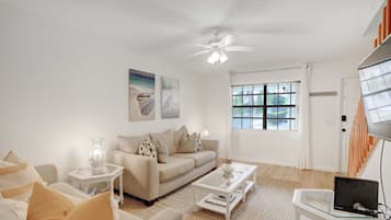 A living room with a sofa, coffee table, and a laptop on a small table.