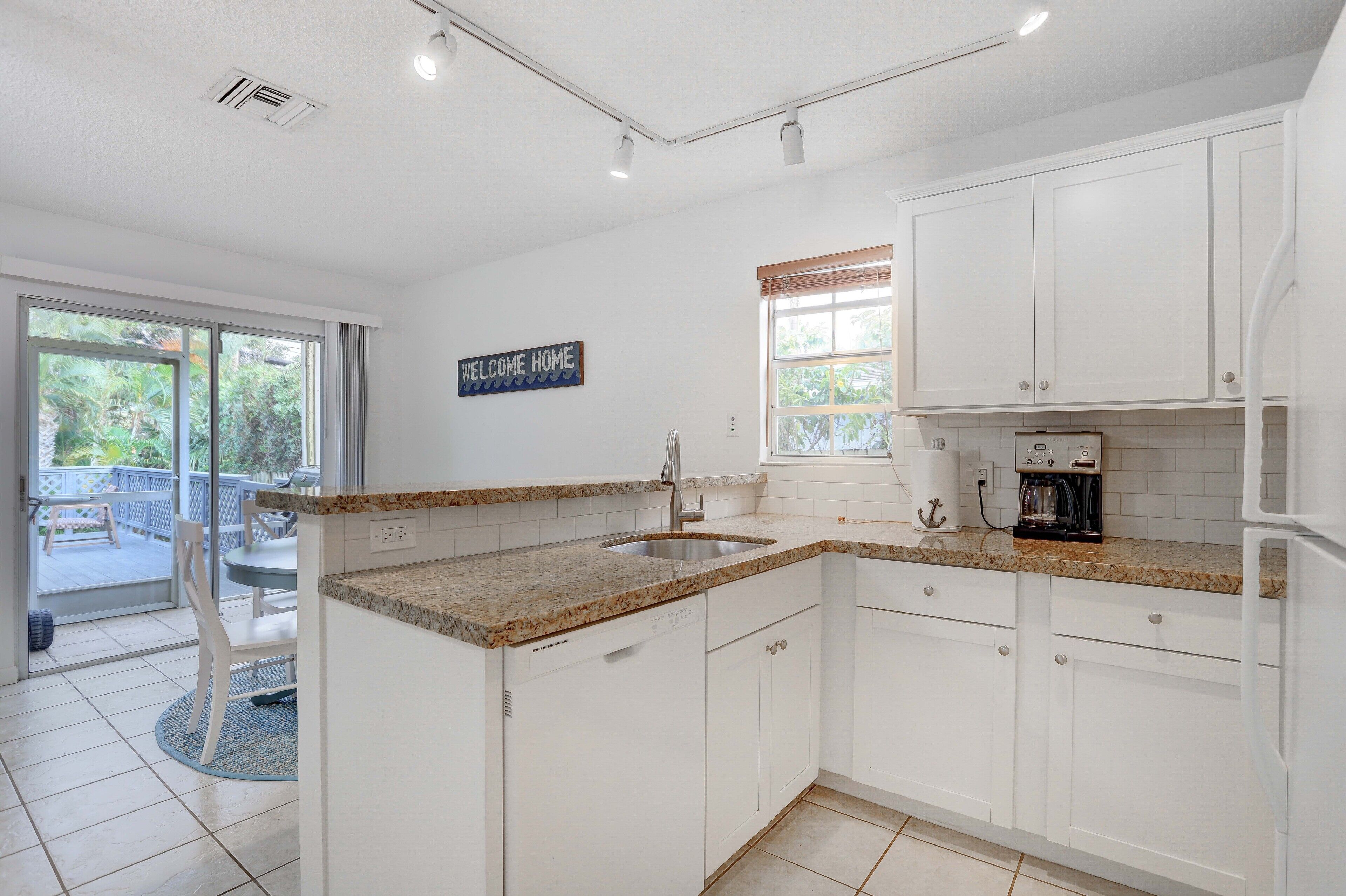 A modern kitchen with white cabinets, granite countertops, and a built-in coffee maker.