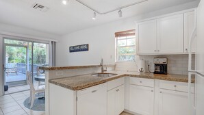 A modern kitchen with white cabinets, granite countertops, and a built-in coffee maker. - Charming Cottage worth every $$ (Delray Beach)