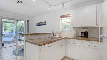 A modern kitchen with white cabinets, granite countertops, and a built-in coffee maker.