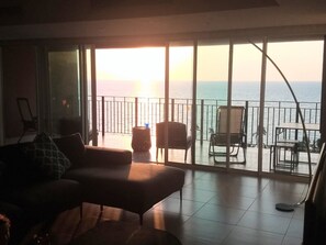 Varanda com vista para o mar, mobiliada com sofá, cadeiras e mesa.