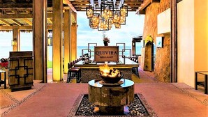 Un restaurante con un letrero que dice "QUIVIRA GOLD'S CLUB" y un brasero en el centro.