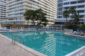 A swimming pool with blue lounge chairs and a metal ladder.