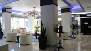 Eine großzügige Lobby im modernen Stil mit einer großen Kronleuchter, gemütlichen Sitzbereichen und einer Rezeption.